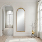 Gold arched floor mirror styled in a room