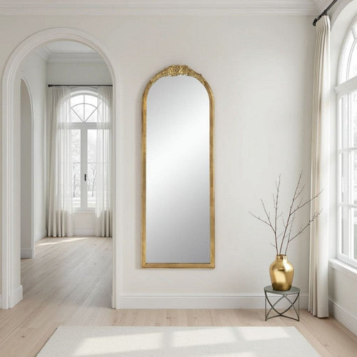 Gold arched floor mirror styled in a room