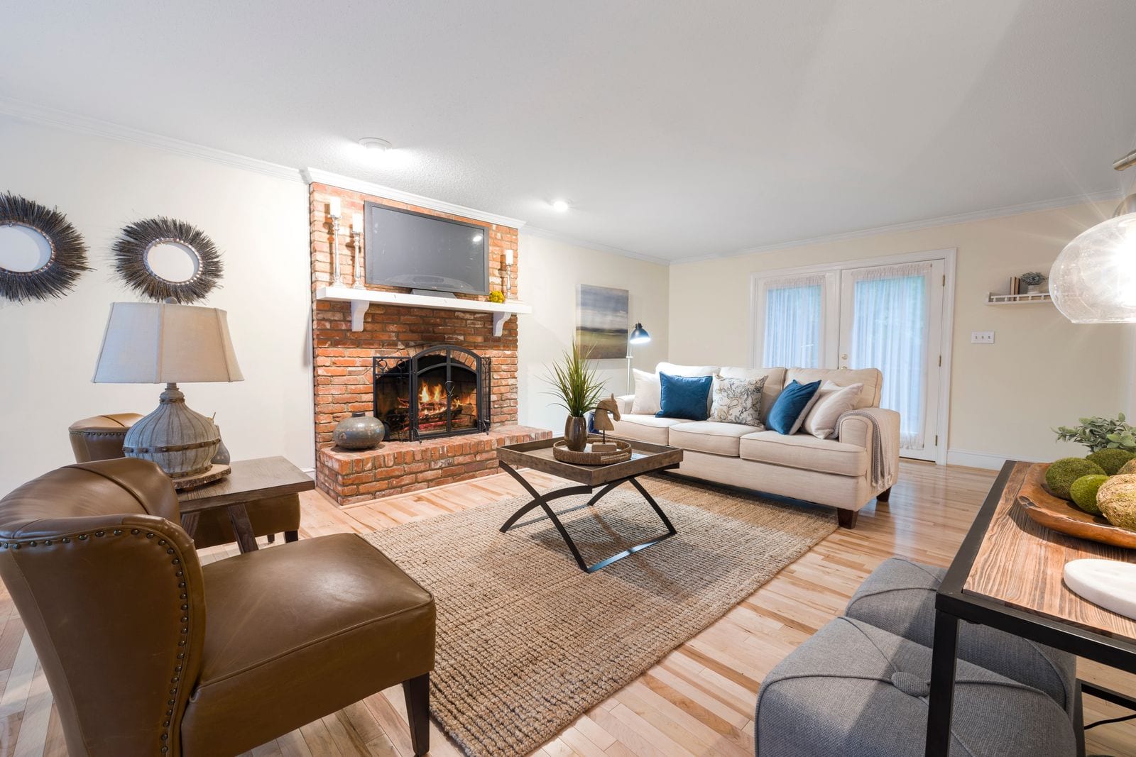 A furnished Lubbock living room with walnut floors, a linen sectional, and a handmade side table in warm afternoon light.
